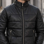 A close-up of a man wearing a black quilted leather jacket with a stand-up collar, front zipper, and zippered hand pockets.
